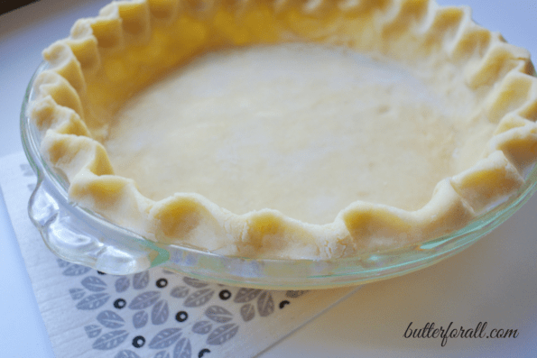 Unbaked lard pie crust in a glass pan.