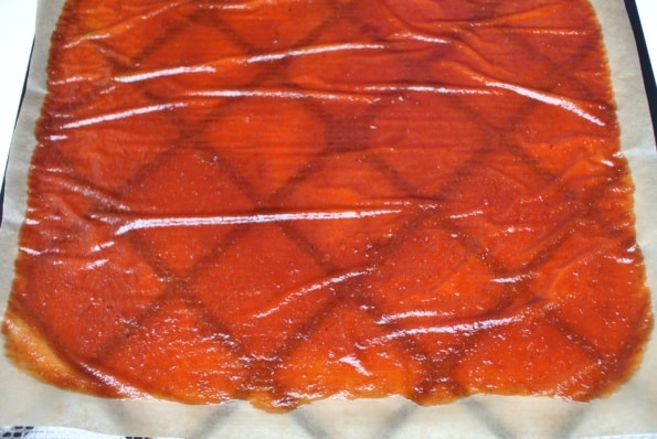 Yellow plum fruit leather, finished dehydrating, on a dehydrator tray.