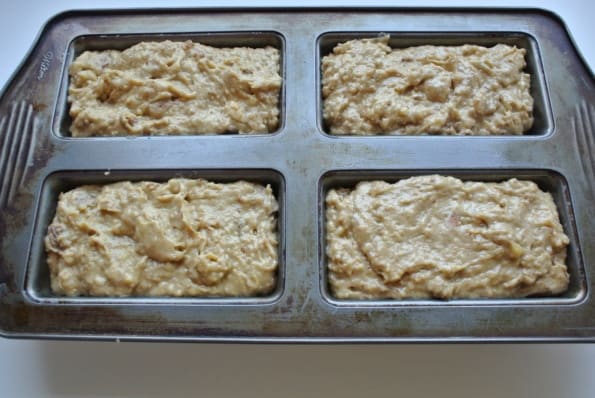 Banana date bread batter in four mini bread pans.