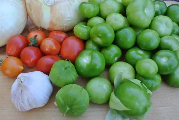 Fresh tomatillos, tomatoes, onions, and garlic.