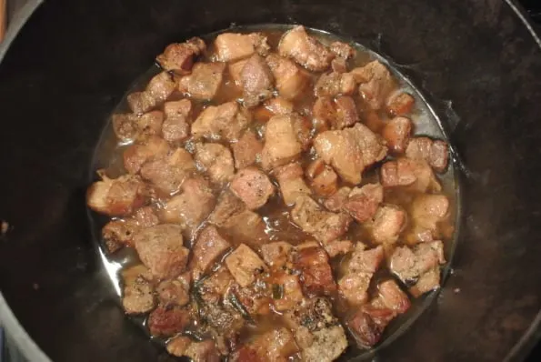 Pieces of pork cooking in a pan.