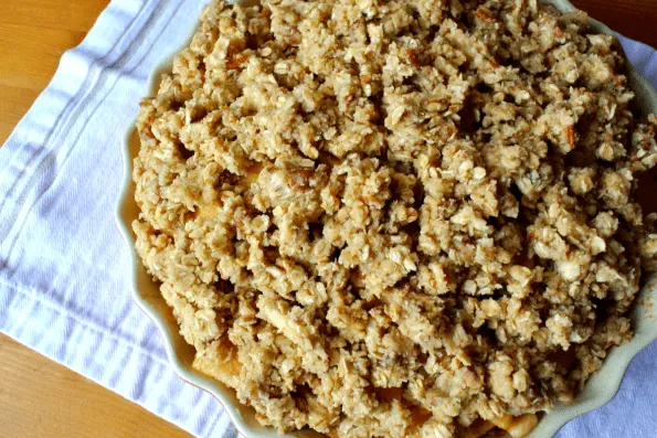 An unbaked apple crisp with oatmeal cookie crumble topping.