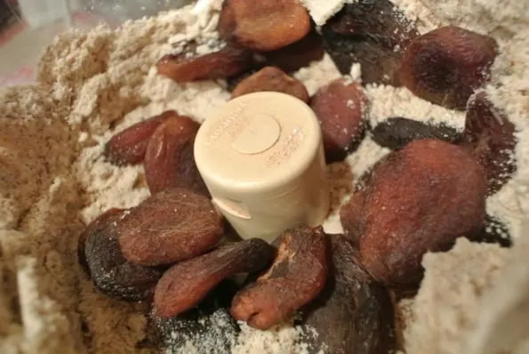 Apricots added to a date cashew mixture in a food processor.