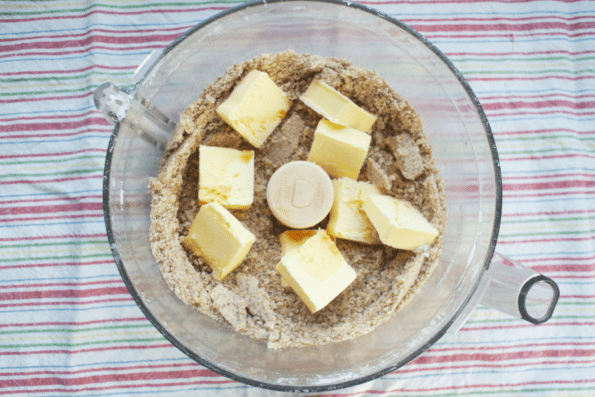 A bowl of processed date and pecan mixture with butter pats.