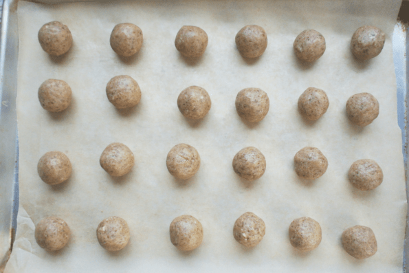 Unbaked snowball cookies on a baking sheet.