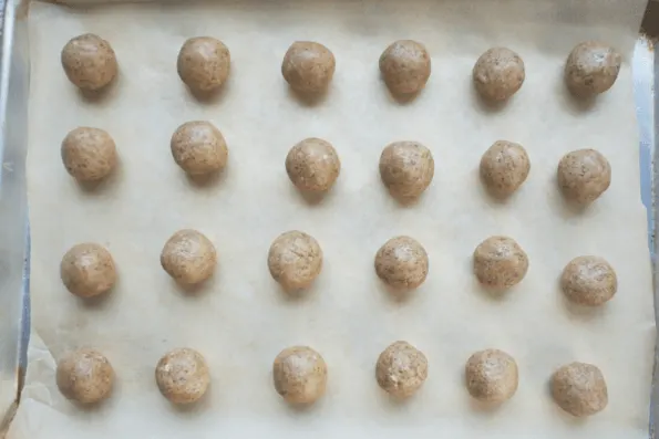 Unbaked snowball cookies on a baking sheet.