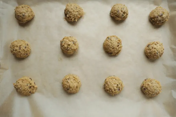 Unbaked dough balls of chocolate chip cashew cookies.