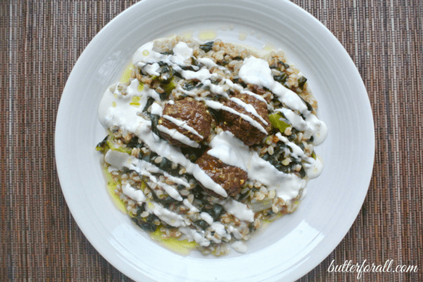 A plate of curried lamb meatballs on soaked farro with tahini sauce.