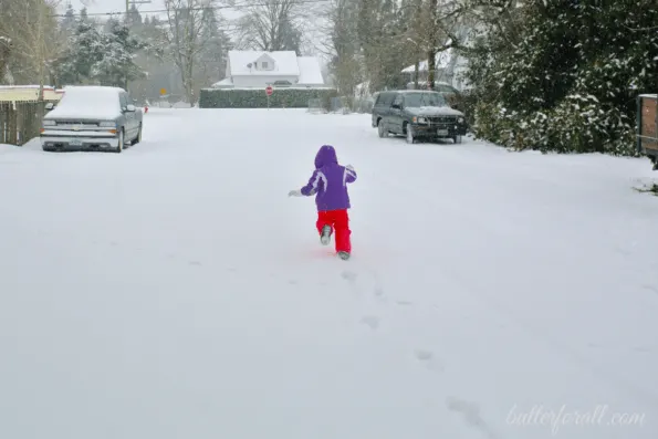 A girl running in a snowy street.