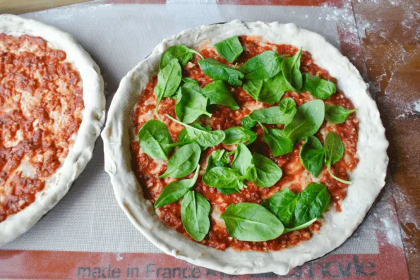 Sourdough pizza crusts with sauce and spinach.
