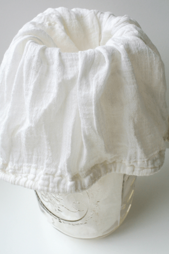 A jar of clabber with a cotton bag on top for straining.