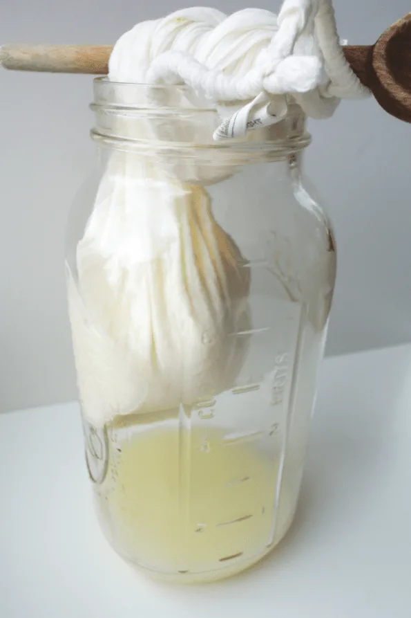 A bag of clabber draining whey into a jar.