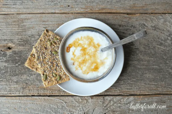 A bowl of clabber milk with honey and crackers.