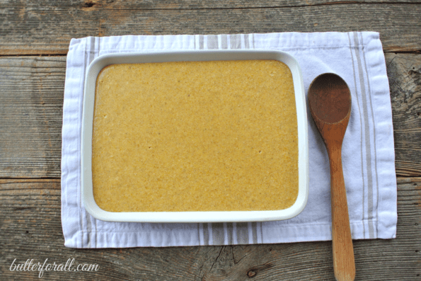 A pan of clabber milk corncake and a wooden spoon on a white cloth.