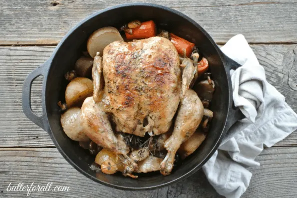 Baked Dutch oven roasted chicken with seasonal vegetables in a pot.