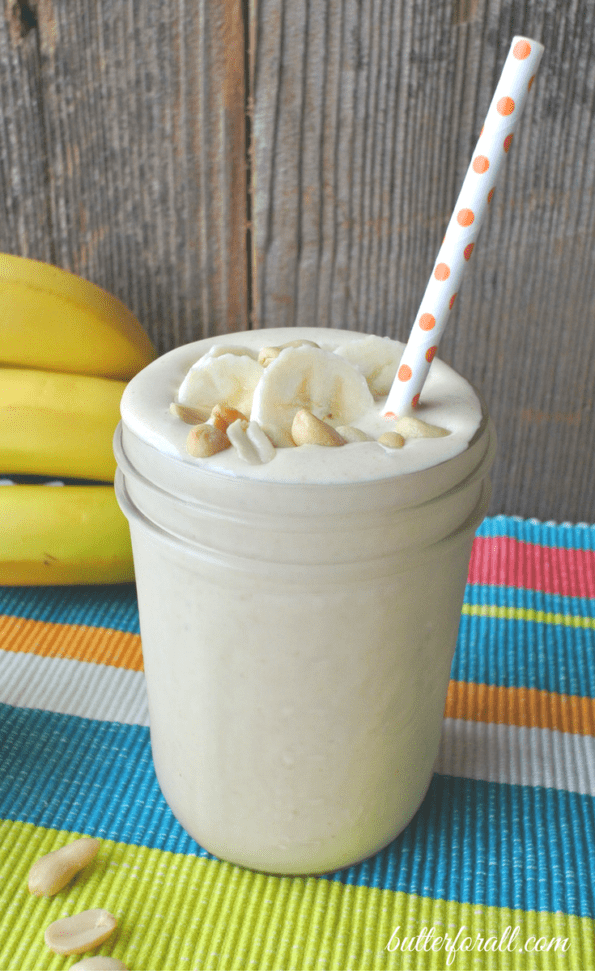 A glass jar of milkshake with a straw.