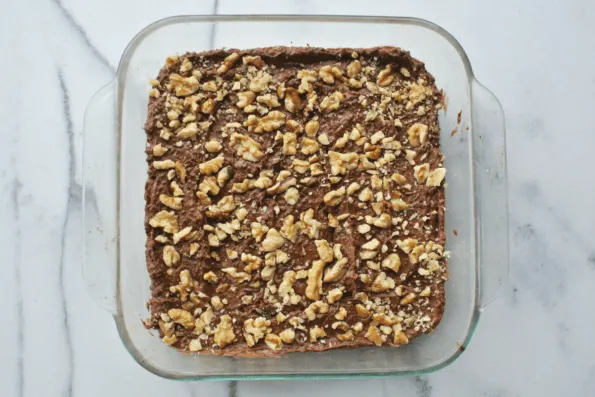 A pan of baked brownies with walnuts on top.
