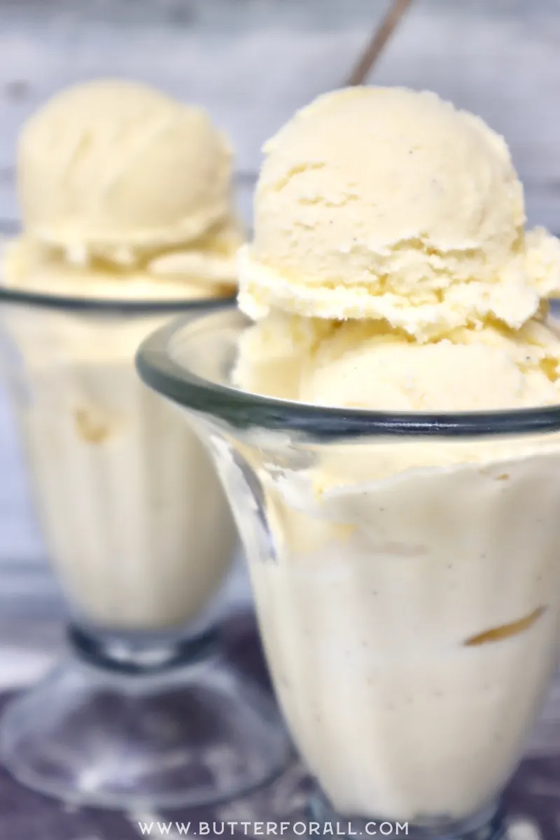 Two tall sundae glasses filled with scoops of creamy ice cream.