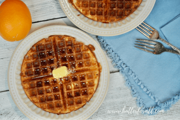 A sourdough waffle on a plate covered in maple syrup.