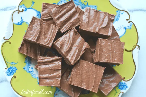 Squares of cut chocolate coconut butter fudge on a decorative plate.