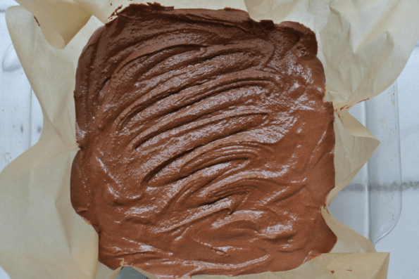 Chocolate coconut butter fudge batter spread onto parchment paper to chill.