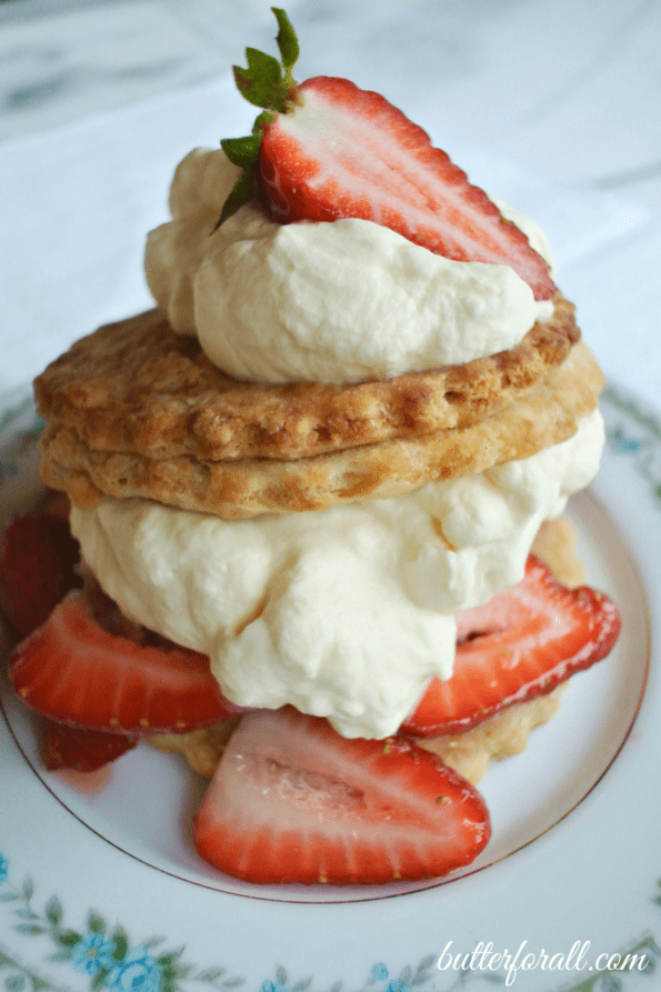 A sour cream shortcakes with strawberries and whipped cream on a plate.