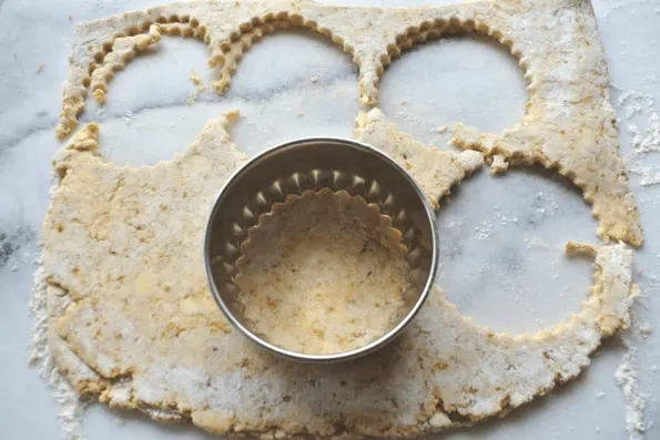 Shortcakes being cut out with a biscuit cutter.