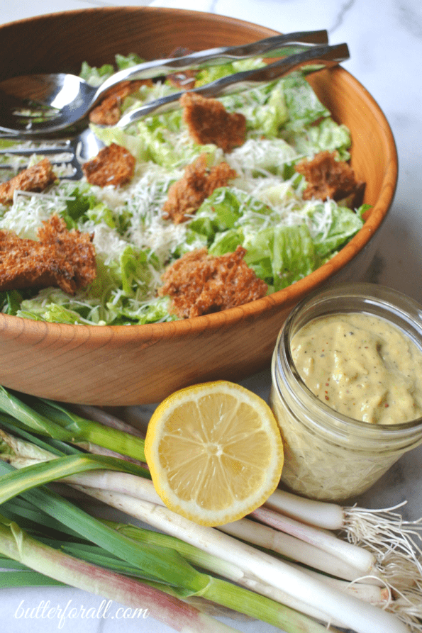Salad in a bowl with spring garlic and lemon caesar dressing.