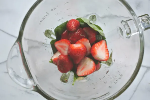 Fresh strawberries in a glass measuring cup.