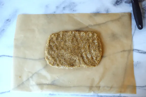 Sesame, cheese, and nut cracker dough formed into a rectangle.