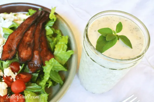 A salad next to a jar of keto ranch dressing.