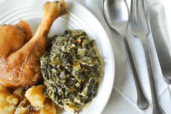 A plate with creamed greens and roasted chicken.