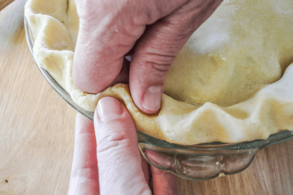 The edges of the crust being crimped by hand.