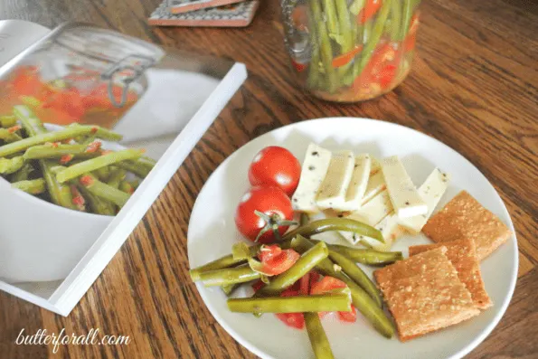 A plate of fermented green beens served with cheese and crackers.