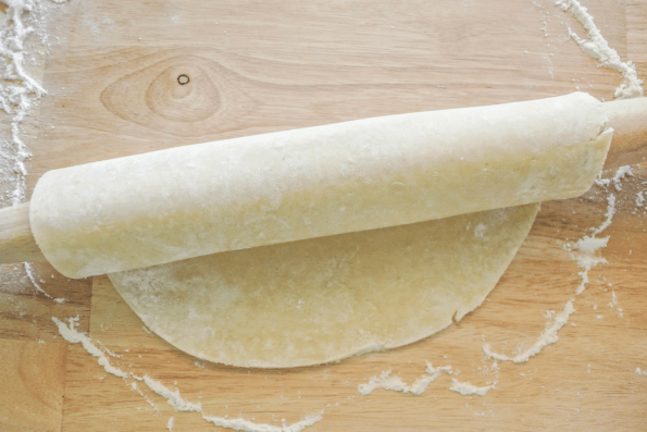 Pie dough rolled around a rolling pin for easy transport to the pie dish.