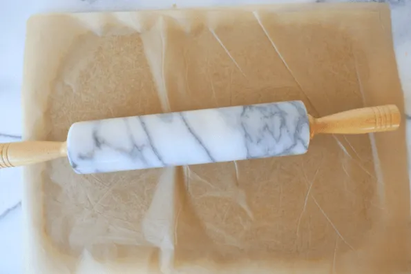 Cracker dough being rolled onto parchment.