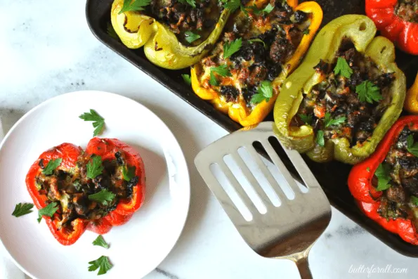 A tray of baked stuffed bell peppers and a plate with one baked bell pepper.