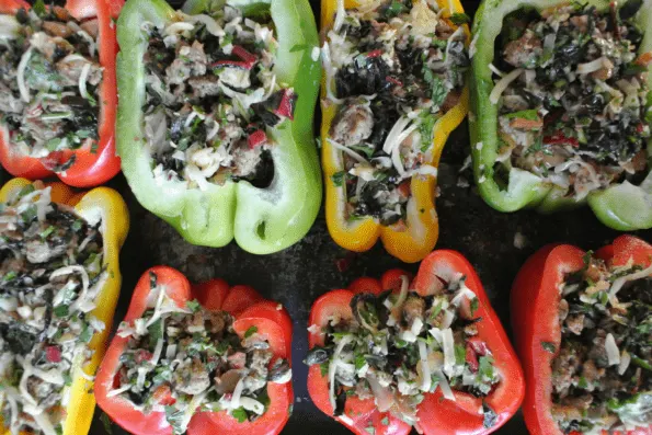 A tray of raw, cut bell peppers stuffed with filling.