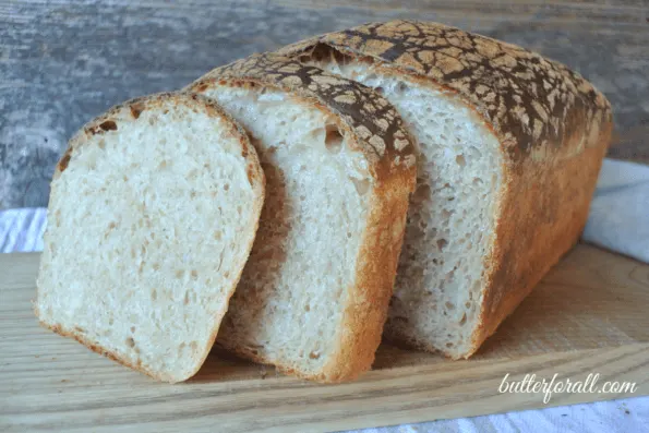 A loaf of butter top sourdough sliced to show the crumb.