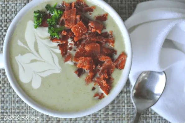 A bowl of broccoli and cauliflower cream soup with bacon garnish.