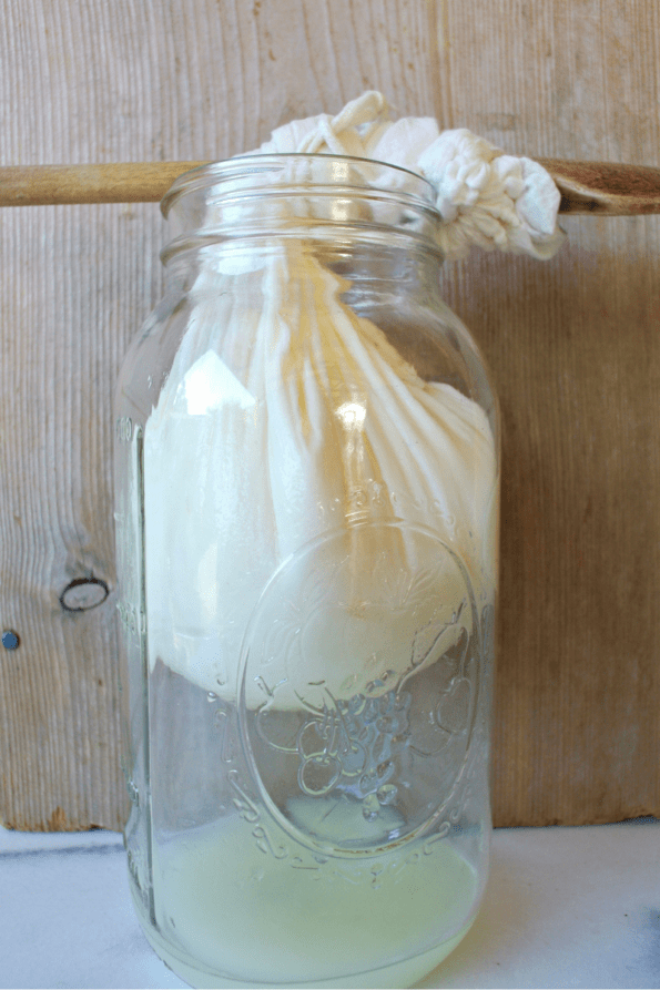 Yogurt in a cotton bag draining the whey into a jar.