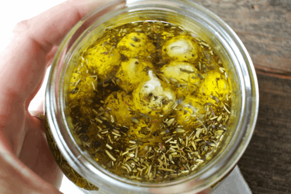 Labneh balls preserved in olive oil with herbs in a glass jar.