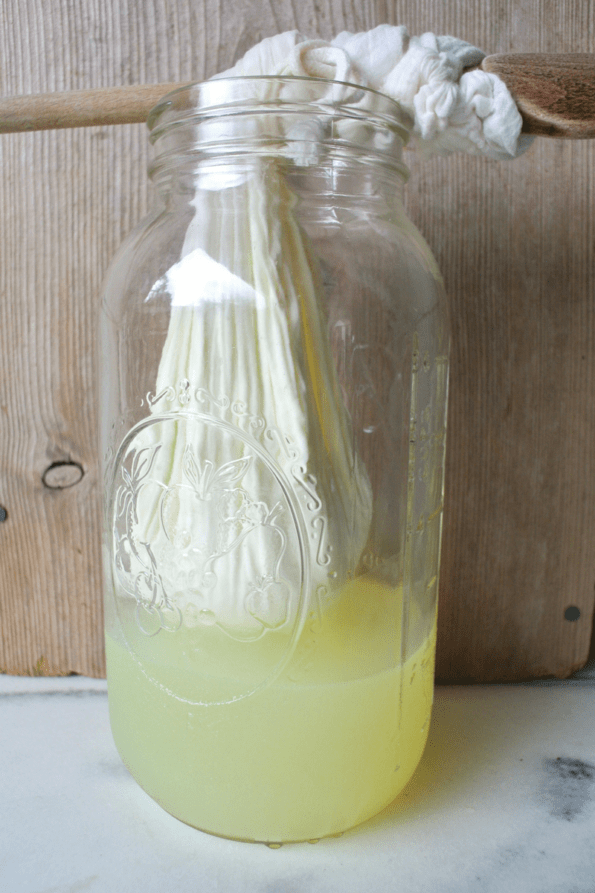 Yogurt in a cotton bag with most of the whey drained into a jar.