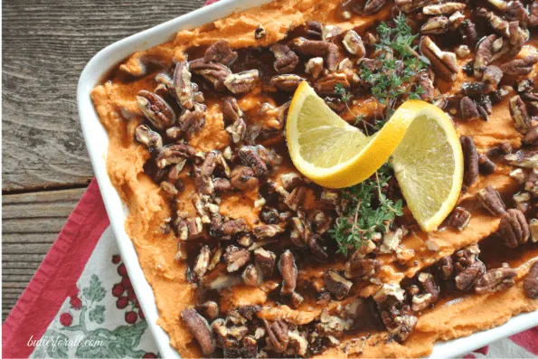 A large casserole dish filled with rich and creamy sweet potato mash and topped with cinnamon maple pecans.