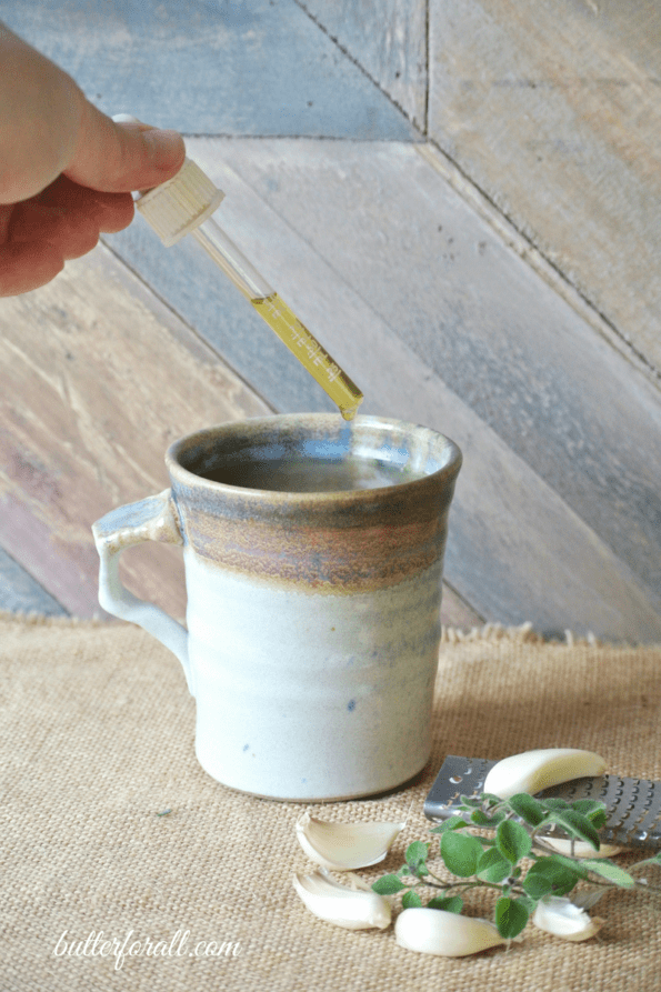 A mug of cold and flu buster with oregano oil being added.