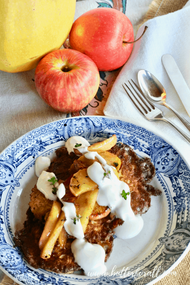 A pretty plate with crispy latkes topped with sautéed apples and sour cream.
