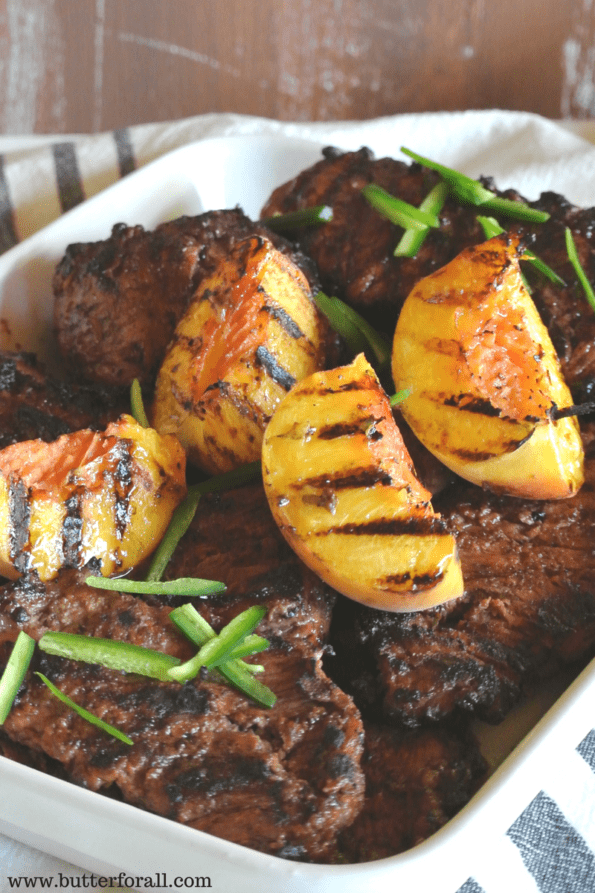 Bavette steaks marinated in jalapeno peach marinade with cut peaches on top.