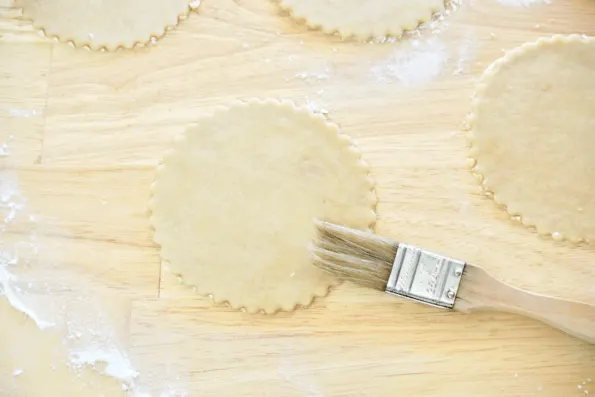 Each mini pie crust is brushed with water to help them seal.