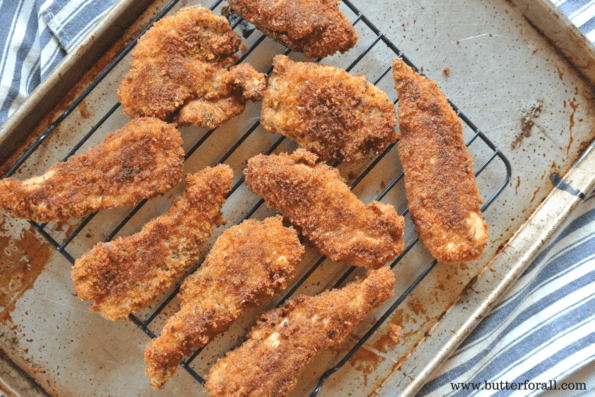 Fresh tender Parmesan and sourdough chicken strips cooling on a wire rack.