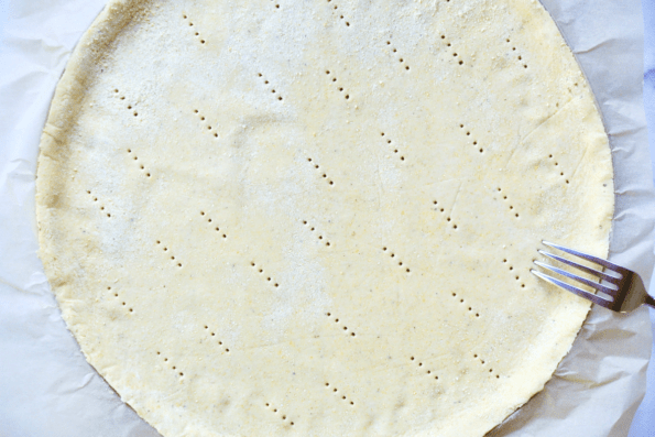 Fitting the sourdough and masa harina cornmeal crust into a pizza pan and docking the crust before baking.